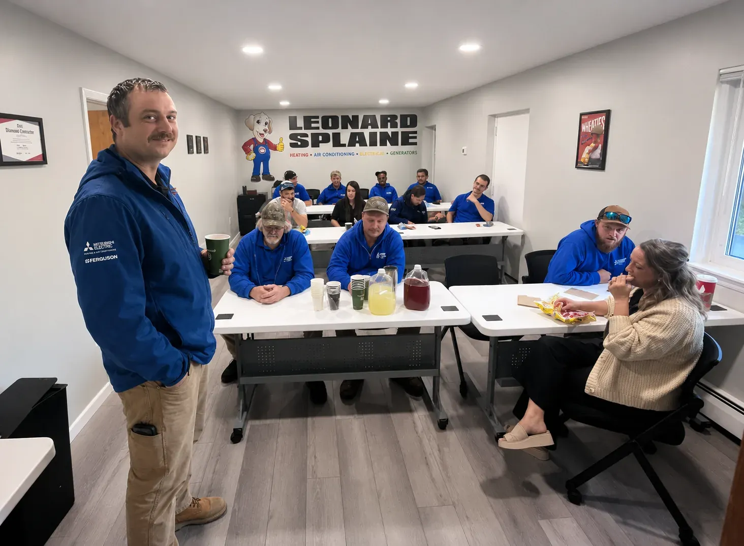 The Leonard Splaine team around the table in the Woodbridge training room, Sonny mural on the wall