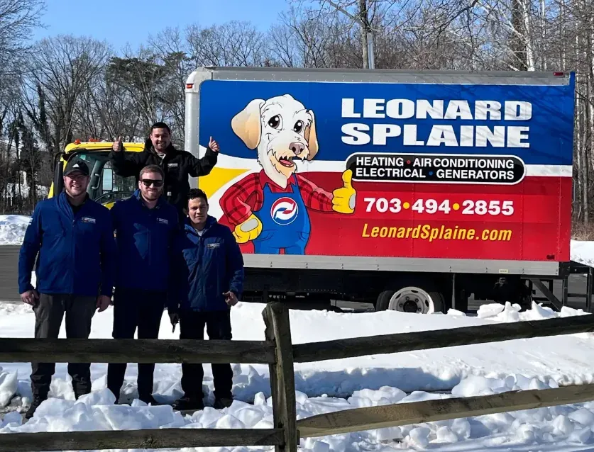 Three Leonard Splaine technicians in front of a branded box truck on a snowy install day