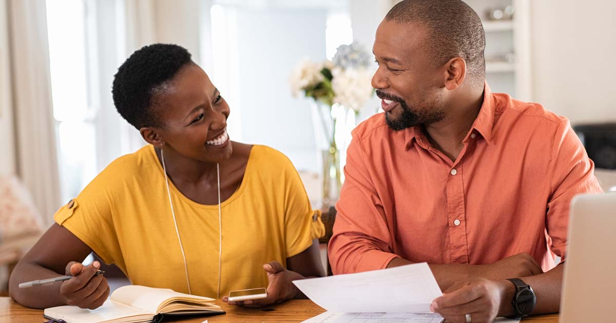 Man and Woman sitting and talking about their finances, smiling.