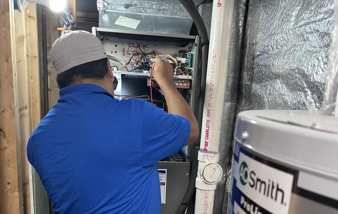 HVAC technician checking electrical wiring inside a furnace or air handler unit.