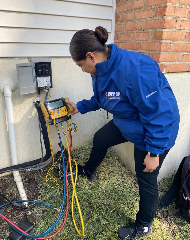 Leonard Plumbing technician performing AC repair service outside a residential home